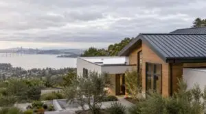 Modern home with a standing-seam metal roof and a flat roof section overlooking the bay