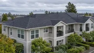 Three-story multi-unit residential building with a shingle roof and balconies