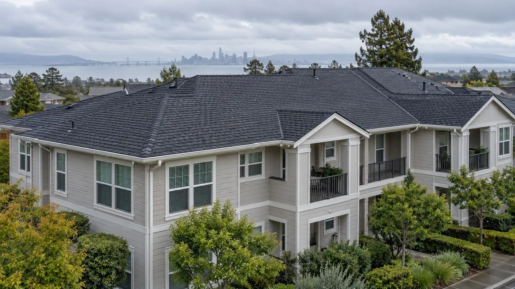 Three-story multi-unit residential building with a shingle roof and balconies